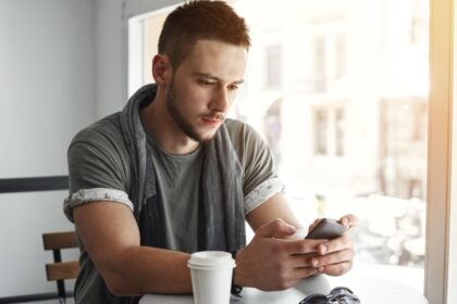 closeup guy sitting table cafe texting message
