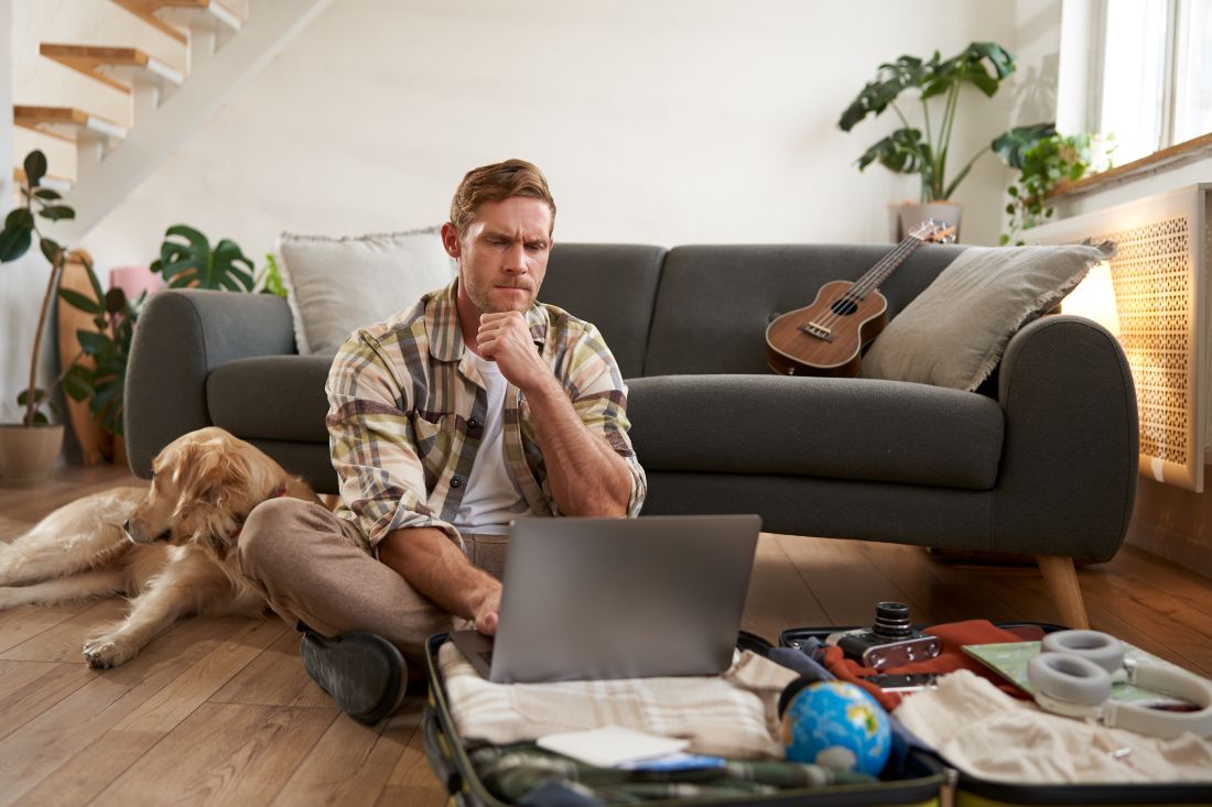image young man tourist going holiday sitting with dog living room looking laptop