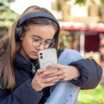 cute teenage girl is taking pictures phone girl headphones 69848146b167b