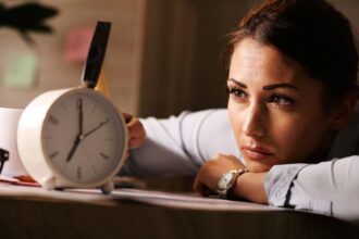 displeased businesswoman hitting alarm clock with hammer office