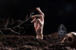 hand sticking out ground near skull